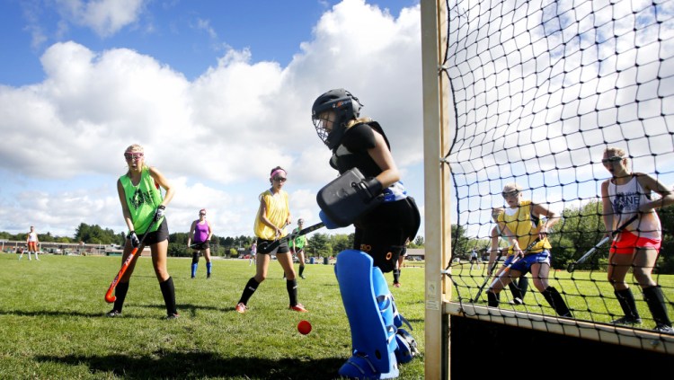 Right now Massabesic is practicing on its old grass field hockey field – Emma Rutledge, left, and Libby Beals look on as Maddy Pomerleau makes a save – but the Mustangs are looking forward to completion of the school's new athletic complex.