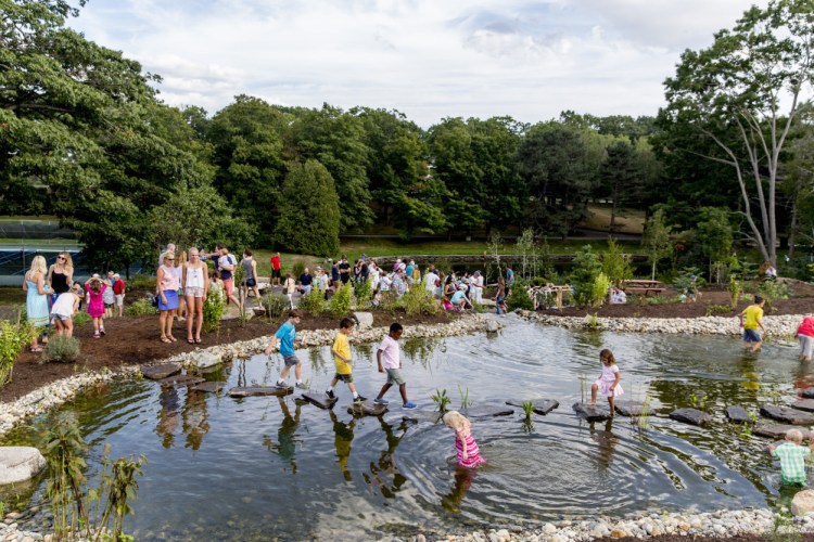 Children use stepping-stones to cross a man-made frog pond in the new Children's Garden at Fort Williams Park on Friday, Sept. 9, 2016.