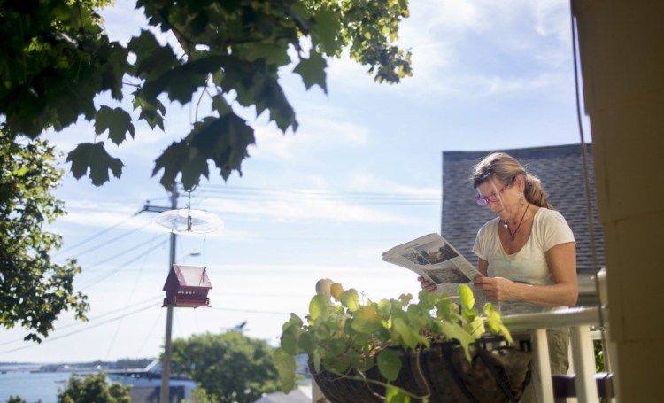 JoAnn Dowe looks at published renderings of the development proposed for the eastern waterfront at her house on Waterville Street, overlooking Portland Harbor. "I'm feeling like I'm going to be moving," she said.