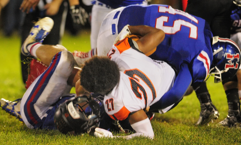 Brunswick's Ben Palizay, middle, loses his helmet while getting tackled by Messalonskee's Cameron Bickford, bottom, and Yan Gusmanov.