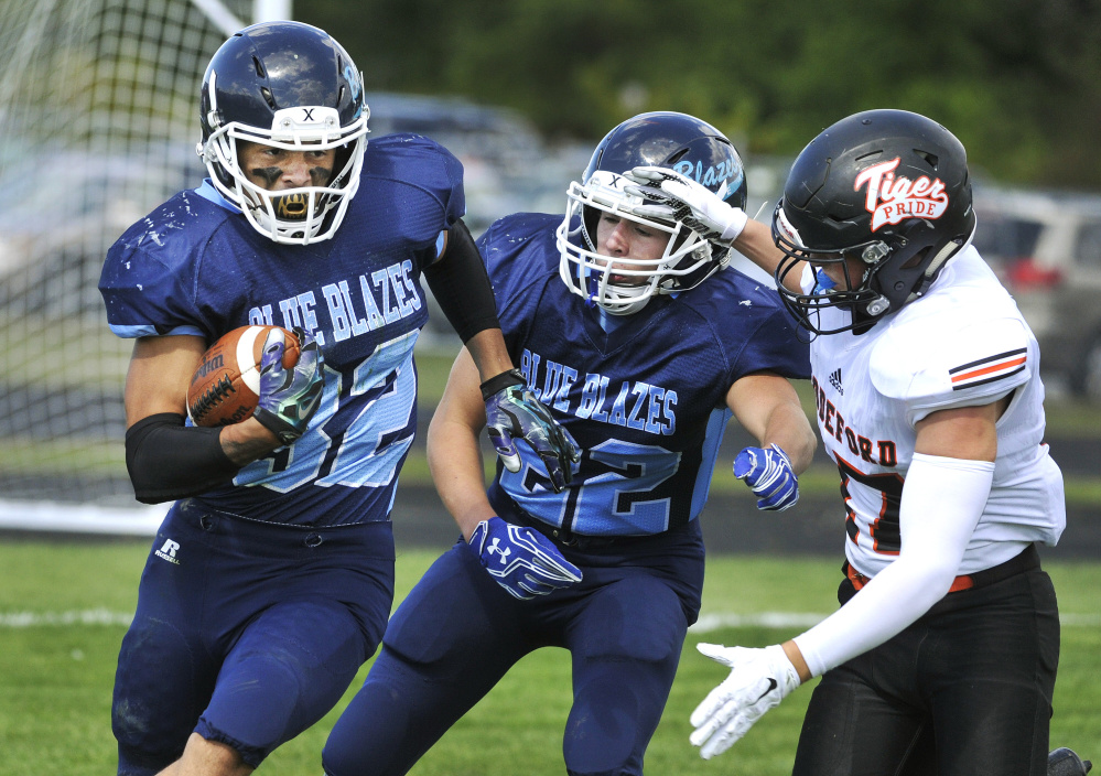 Westbrook running back Miece Loureiro uses a block from Hayden Phelps to avoid Biddeford defender Cam Lantagne during a Class B South game Saturday in Westbrook. Loureiro finished with nearly 200 yards rushing and receiving, but Biddeford won, 20-7.