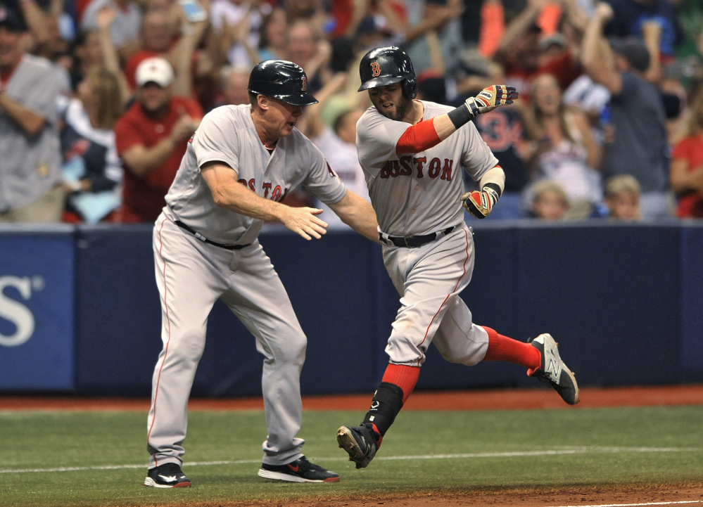 Boston third base coach Brian Butterfield, left, congratulates Dustin Pedroia, who circles the bases after hitting a grand slam off Tampa Bay reliever Danny Farquhar in the seventh inning oon Saturday in St. Petersburg, Fla. The Red Sox went on to a 6-4 win,