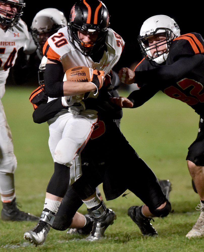 Skowhegan's Kobe Houghton and Garrett McSweeney, right, try to tackle Brunswick running back Hunter Garrett, who scored three touchdowns.