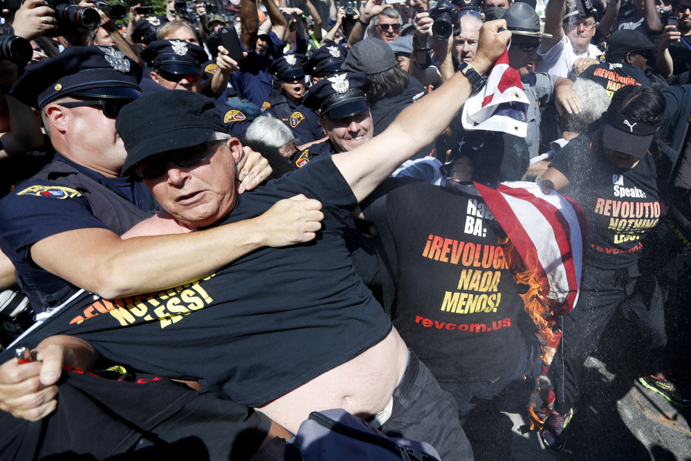 A police officer takes a protester into custody in July after he started to burn a flag in Cleveland during the Republican convention. Donald Trump tweeted Tuesday that anyone who burns a flag should face "consequences," such as jail.