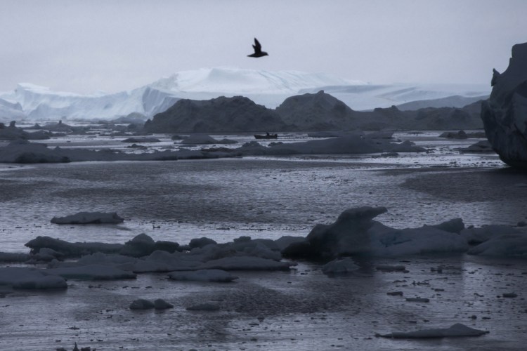 A fisherman drives a boat during Secretary of State John Kerry's tour of the Jakobshavn Glacier and the Ilulissat Icefjord, located near the Arctic Circle in Ilulissat, Greenland, in June. A new federal report says warming at the top of the world is happening twice as fast as the rest of the globe.