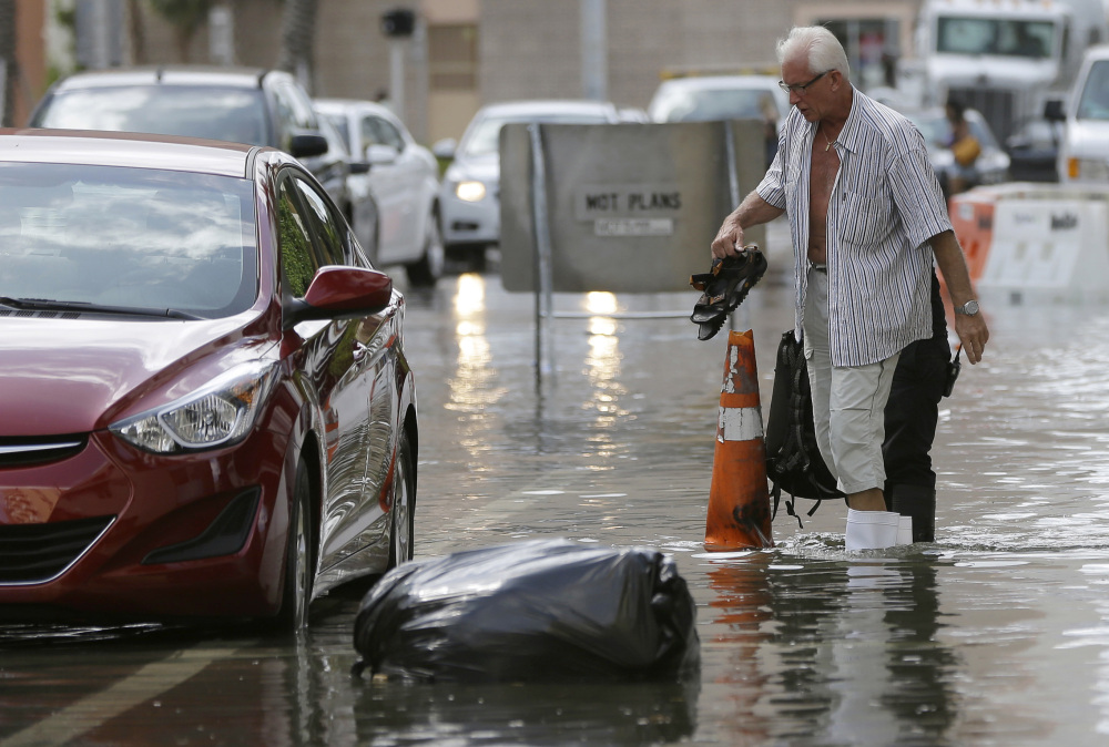 A hotel guest carries his shoes as he is escorted to his car in Miami Beach, Fla., in September 2015. 