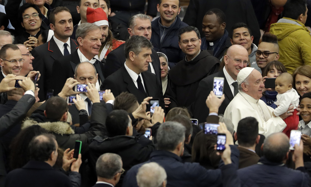 Pope Francis holds a baby during an audience to exchange Christmas greetings with Vatican employees Thursday.