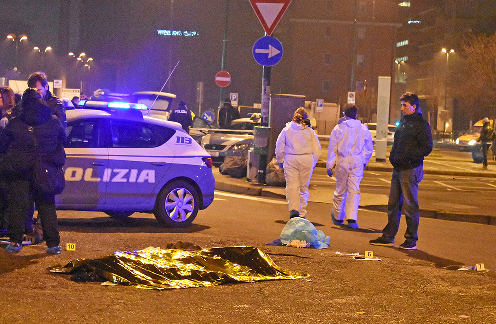 The body of Anis Amri, the suspect in the Berlin Christmas market truck attack, is seen covered with a thermal blanket next to Italian officers in a suburb of Milan Reuters