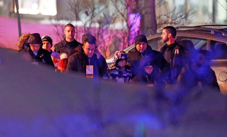 Police escort people from the mosque Sunday night in Quebec City, where gunmen shot and killed six people. 