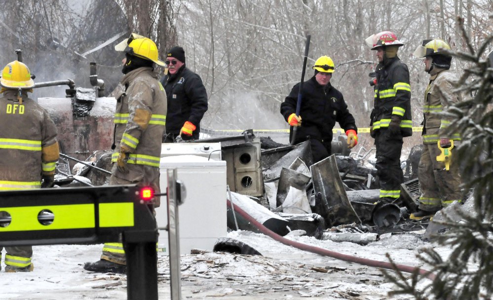 Stu Jacobs, left center, and Jeremy Damren of the Fire Marshal's Office and firefighters investigate the section of an apartment building in Palmyra where the bodies of two people were recovered on Tuesday. 