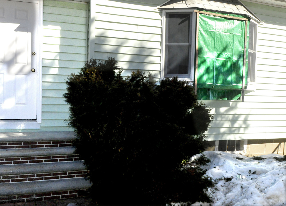 A tarp covers a broken front window Monday at the Audrey Hewett residence at 47 Lyons Road in Sidney. Police allege a male intruder, Dreaquan Foster, was confronted Sunday evening by Hewett's son Eric, who was injured when struck by a blunt object. In the scuffle, Eric Hewett shot Foster in the chest, police said.