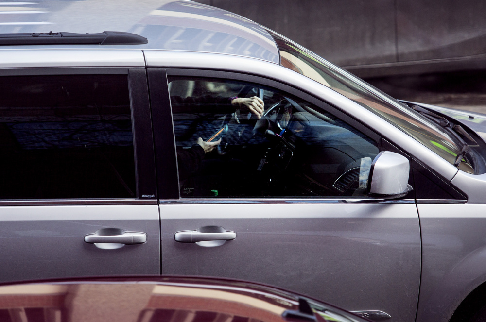 It's one hand on the wheel, one hand on the phone for this motorist on Temple Street in Portland. Because Maine doesn't prohibit drivers from using hand-held devices, violators of the state's texting ban can easily avoid fines by claiming they were actually looking up directions or dialing a phone number.