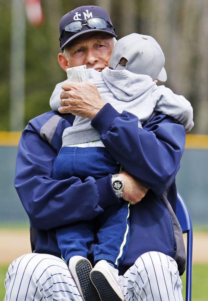 Ed Flaherty shares a hug with his grandson Kaden Booth while waiting for his turn to speak at Sunday's field dedication ceremony.