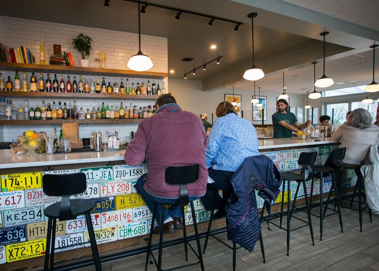 Patrons sit at the bar at Tipo, which is tiled with license plates from around the country.