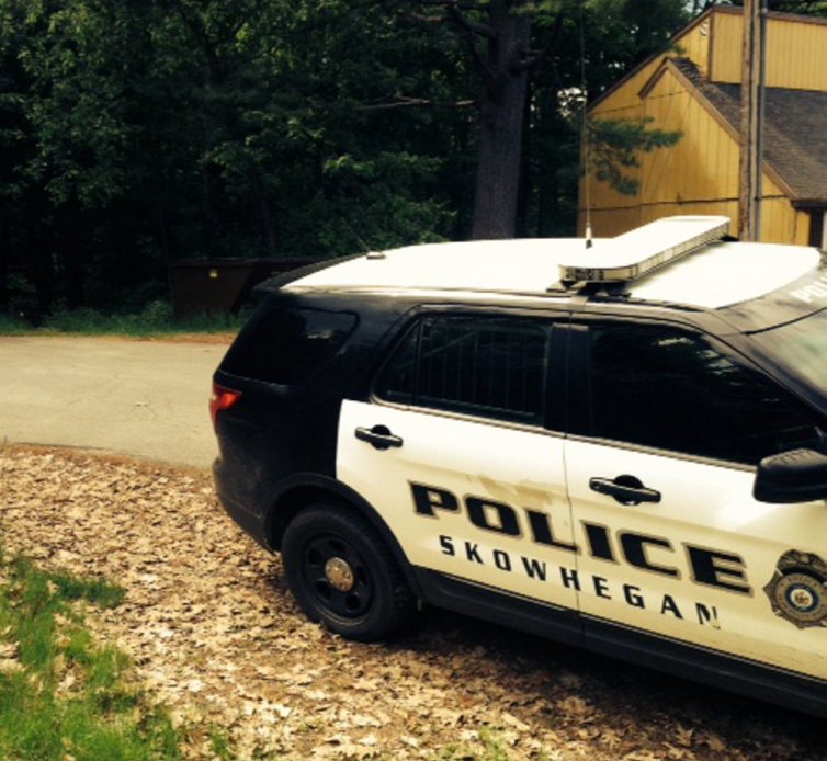 A Skowhegan police cruiser stands parked on Prescelly Drive in Skowhegan near the spot where a body was found Saturday in the woods.