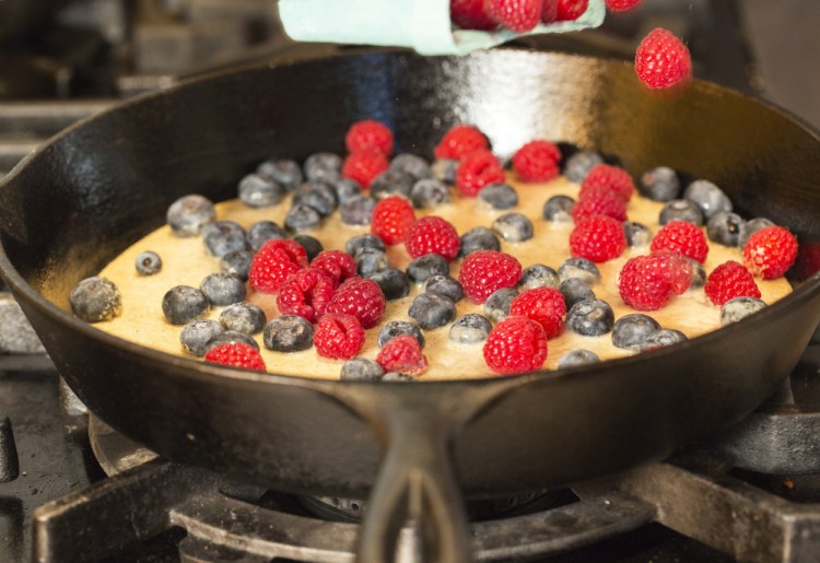 Christine Burns Rudalevige sprinkles some berries onto batter for the clafoutis.
