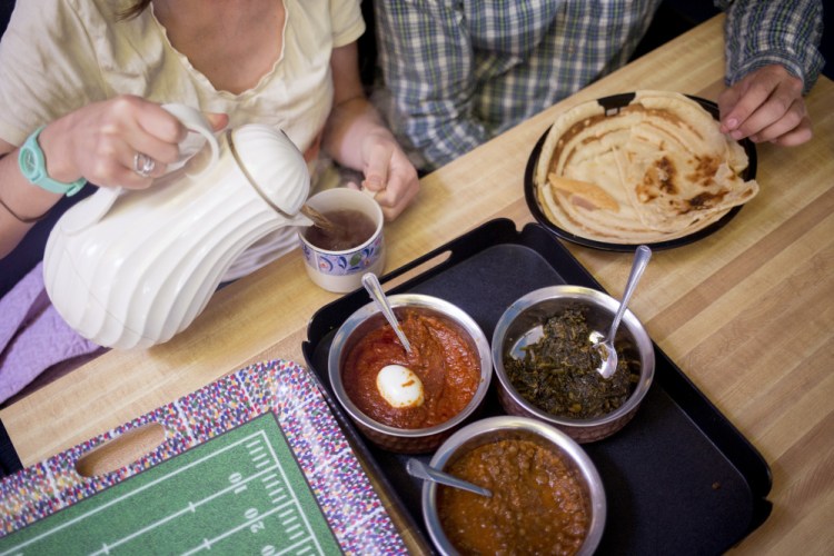 Annie Baron pours a cup of tea as she and Stephen Piwowarski get ready to eat their aanjeera, a golden, soft pancake served with chili, spinach and brown lentils.