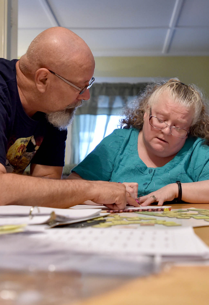 Howard Gagnon helps his wife, Mona, with a reading lesson at the family's home on Gilman Street in Waterville in July.