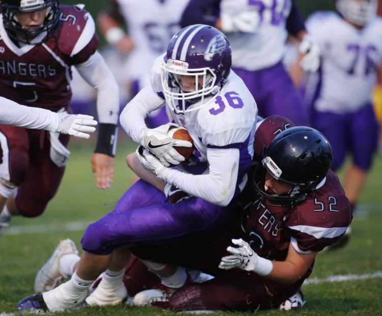 Kyle Glidden of Marshwood High is tackled by Jackson Williams of Greely in the first half of their game Friday night in Cumberland. Marshwood won, 47-14.