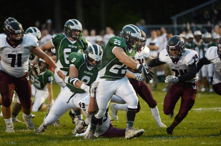 Bonny Eagle's Nick Thorne drags a Windham defender on his way into the end zone for one of his three first-half touchdowns Friday in a 55-7 victory.