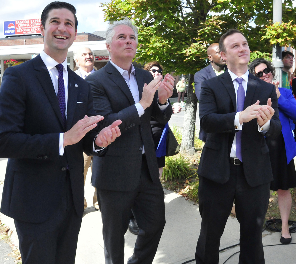 From left, Waterville Mayor Nick Isgro, Colby College President David Greene and Vice President of Planning Brian Clark applaud as the final beam is set on the college's new downtown dormitory Thursday on The Concourse in Waterville.