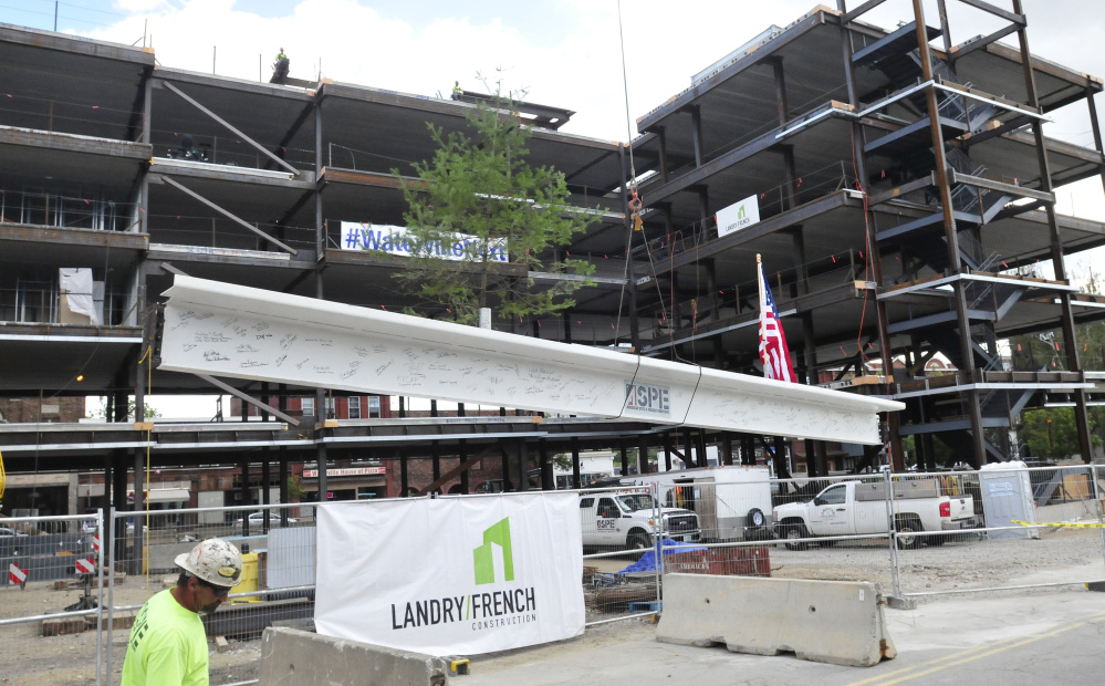 The final beam of the Colby College downtown dormitory, which will include retail and community spaces, rises to top off the building's frame Thursday during a ceremony in Waterville.