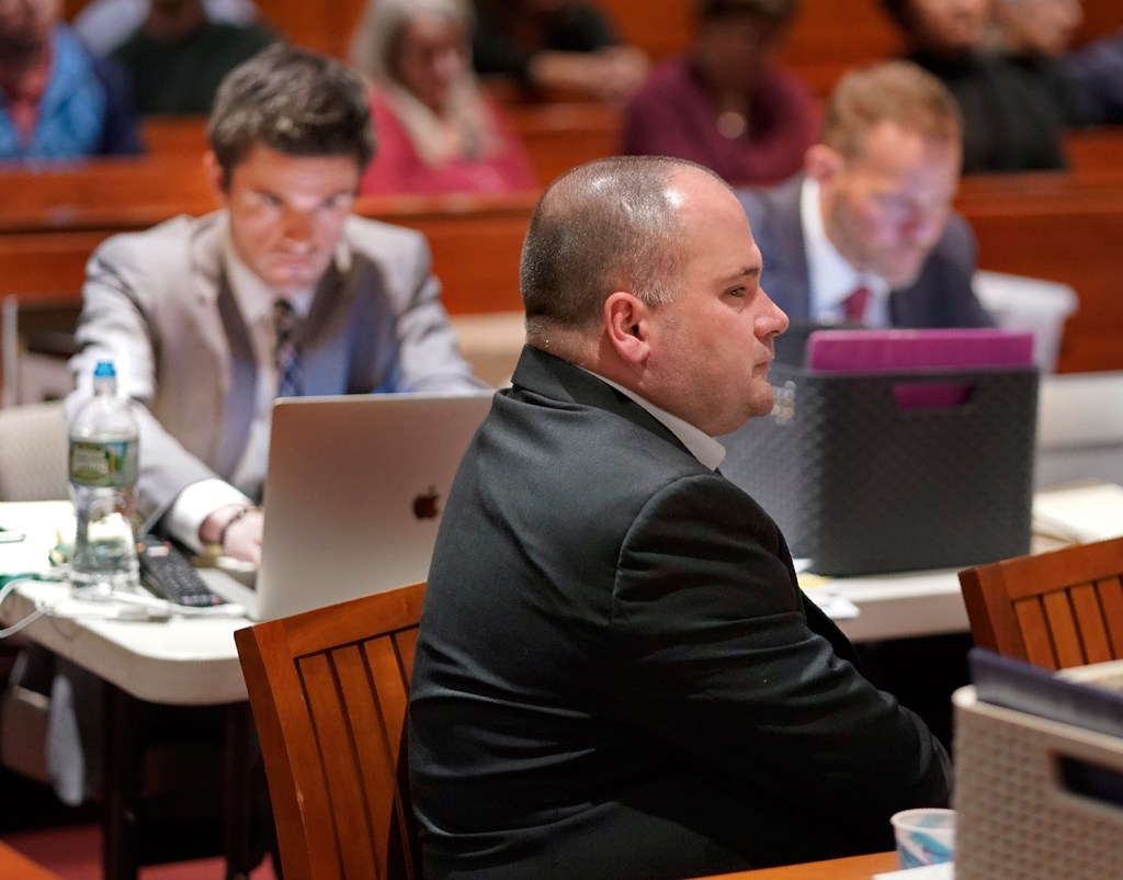 Anthony Sanborn listens to testimony by retired Portland detective James Daniels on Thursday at the Cumberland County Courthouse. Behind him, members of his defense team work on their computers.