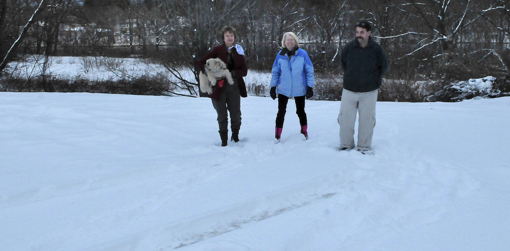 Waterville Community Land Trust members Francis Williams, left, Ann Beverage and Scott McAdoo walk Monday on one of two lots the land trust recently acquired, one of which will be used as a house lot, the other as green space with river frontage.