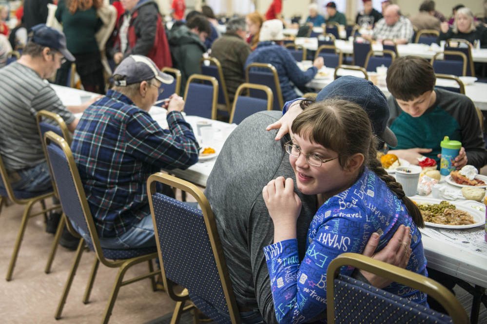 Madison Rowe, 13, gives her father, James Rowe, a hug after a turkey dinner Monday at the 11th annual Central Maine Family Christmas Dinner at the Elks Lodge in Waterville.