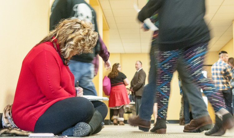 Sitting on the floor of a hallway outside the hearing room, Penny Snider, a medical marijuana caregiver from Pittston, writes out her testimony on Tuesday as she prepares to testify before the Marijuana Law Implementation Committee in the Cross State Office Building in Augusta.