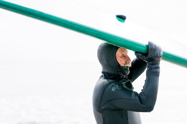 Don Parsons, 68, of Ogunquit, places his surf board on top of his car as ice crystals form on his mustache and face in the single-digit temperatures with below-zero windchills at Long Sands beach in York Monday, January 15, 2018. Parsons comes out to surf regardless of the weather, he says, but that once he's out of the water, it can get freezing. "I once asked my friend why we come out in this," Parsons said. "He said for bragging rights and I was like I'm 68 I don't need bragging rights." Staff photo by Gabe Souza