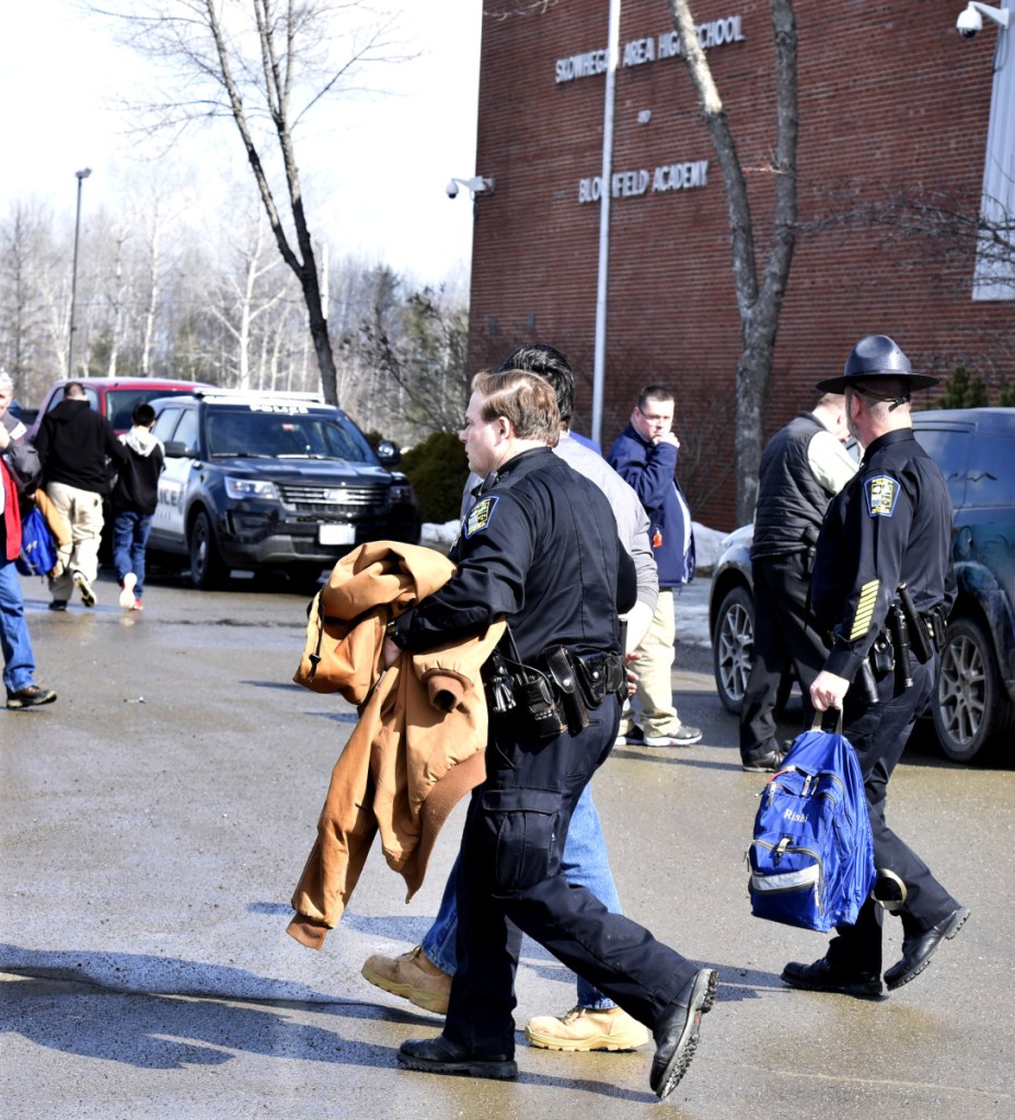 SAD 54 resource officer David Daigneault, center, leads a Skowhegan Area High School student in handcuffs Thursday after threats resulted in a school lockout earlier in the day.