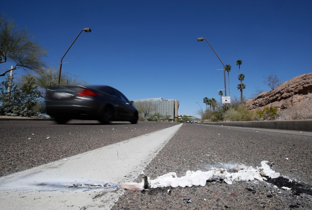 Cars pass the scene where a pedestrian was stuck by a self-driving vehicle this month in Tempe, Ariz. The vehicle was in autonomous mode with an operator behind the wheel when a woman walking outside a crosswalk was hit. Uber suspended all of its self-driving testing Monday.