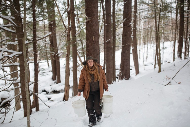 Nina Britton gathers water from the nearby brook on March 10 for the sauna at Nurture through Nature in Denmark. Britton continually pours the water on to the hot rocks during  the Finnish-style sauna.