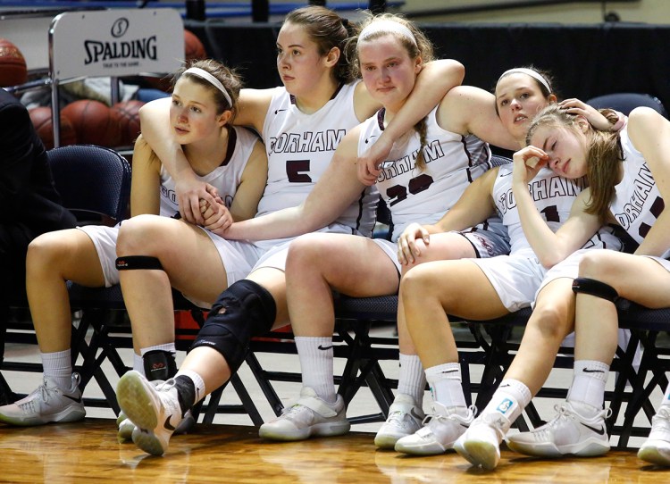 Gorham teammates hold onto each other as Edward Little players cut down the nets after Gorham lost the Class AA Basketball championship game March 2.