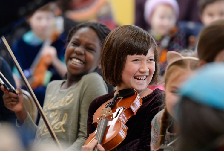 Laughs are part of the learning during the Maine Acoustic Festival's free workshop at Portland's East End Community School as Ivy Birney 9, center, of North Yarmouth demonstrates.