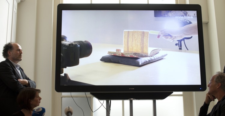 A video shows how two pages taped off with brown masking paper from Anne Frank's diary were photographed to reveal her writing, during a news conference at The Anne Frank Foundation's office in Amsterdam, Netherlands, on Tuesday. Standing at left is the foundation's director, Ronald Leopold.