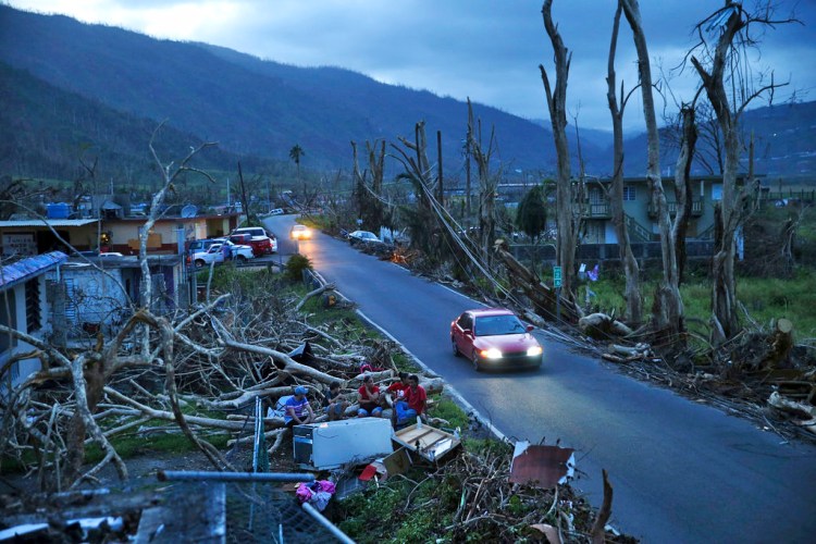 Neighbors sit on a couch outside their destroyed homes as sun sets in the aftermath of Hurricane Maria, in Yabucoa, Puerto Rico, on Sept. 26, 2017.