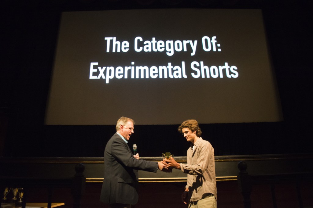 Maine Public education program director Dave Boardman presents Brett Smith the first-place award in the documentary category Saturday at the 41st annual Maine Student Film & Video Festival awards ceremony at the Waterville Opera House.