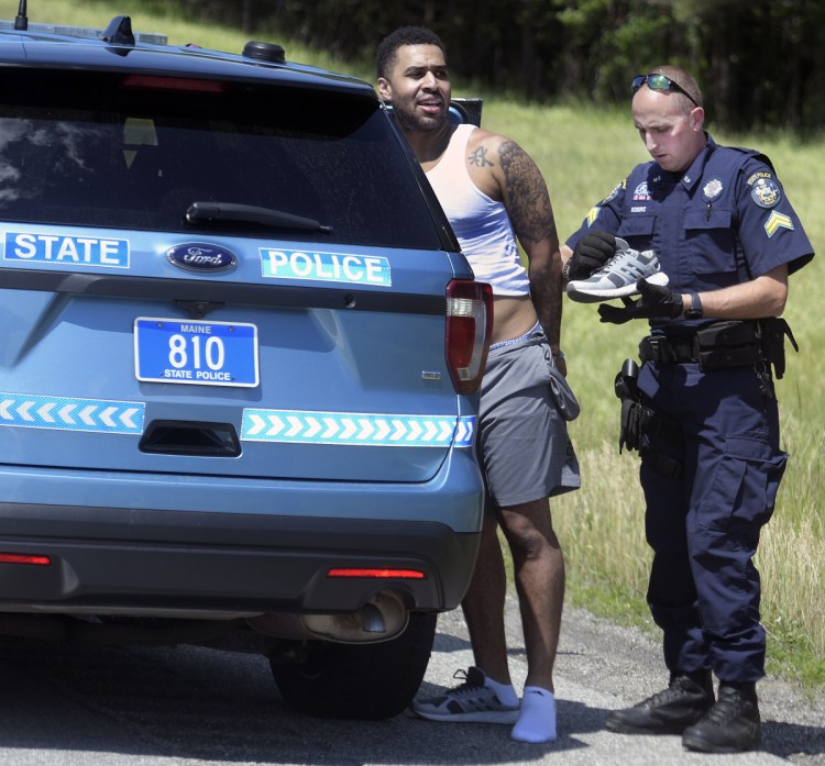 State Police Cpl. Christopher Rogers searches the clothes of a man he arrested Friday on the Maine Turnpike in Hallowell following a pursuit.