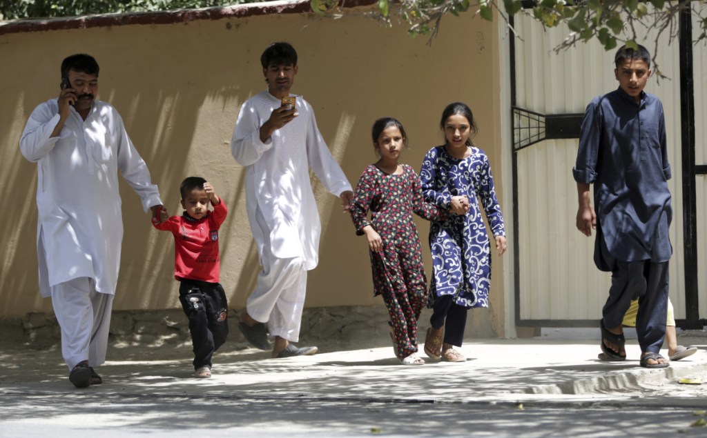 Families leave their homes Thursday in Kabul, where two gunmen engaged police in a six-hourlong standoff at an Afghan intelligence service compound before the security forces killed them. The violence followed Wednesday's killing of 34 youths.