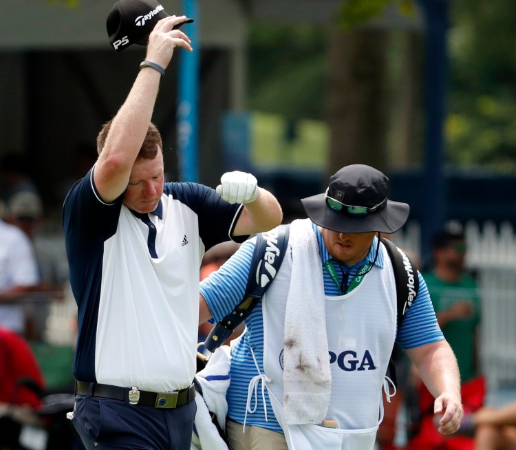 Portland's Shawn Warren, wipes his face as he walks down the 18th fairway with caddie Shawn McCurdy during the first round of the PGA Championship at Bellerive Country Club on Thursday.