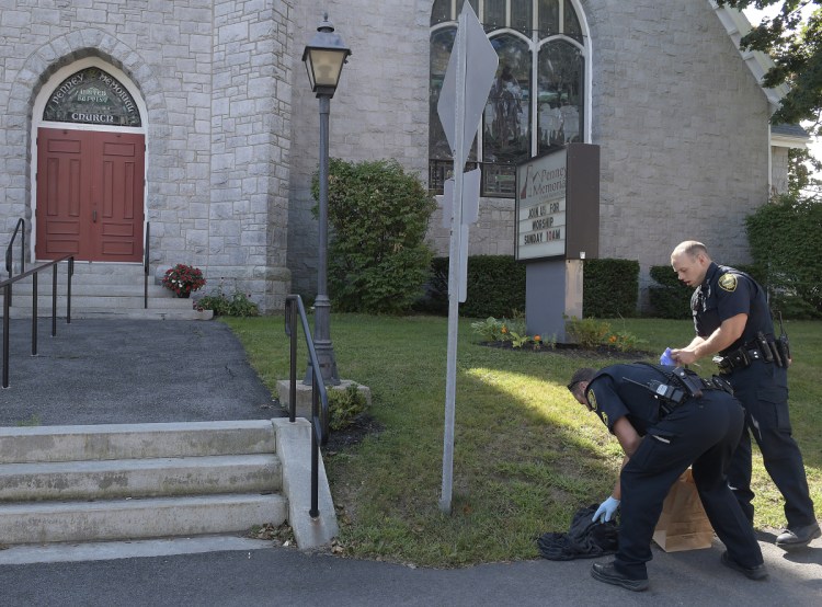 Augusta Police Department officers collect a black hooded sweatshirt Sunday in front of Penney Memorial United Baptist Church in Augusta moments after an armed robbery at a Walgreens next door.