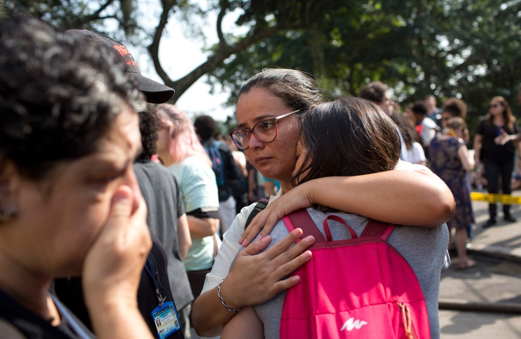 National Museum employees embrace outside the burned museum Monday. The museum houses artifacts from Egypt, Greco-Roman art, and some of the first fossils found in Brazil.