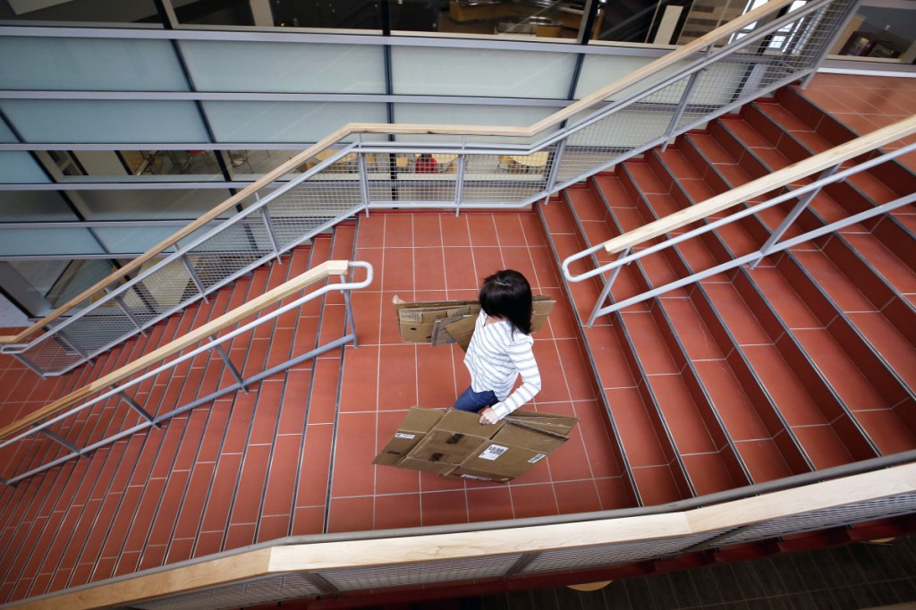 Cheryl Gifford, Sanford High School's Jobs for Maine Graduates teacher, carries cardboard down the center stairway of the new facility as faculty members move in Monday.