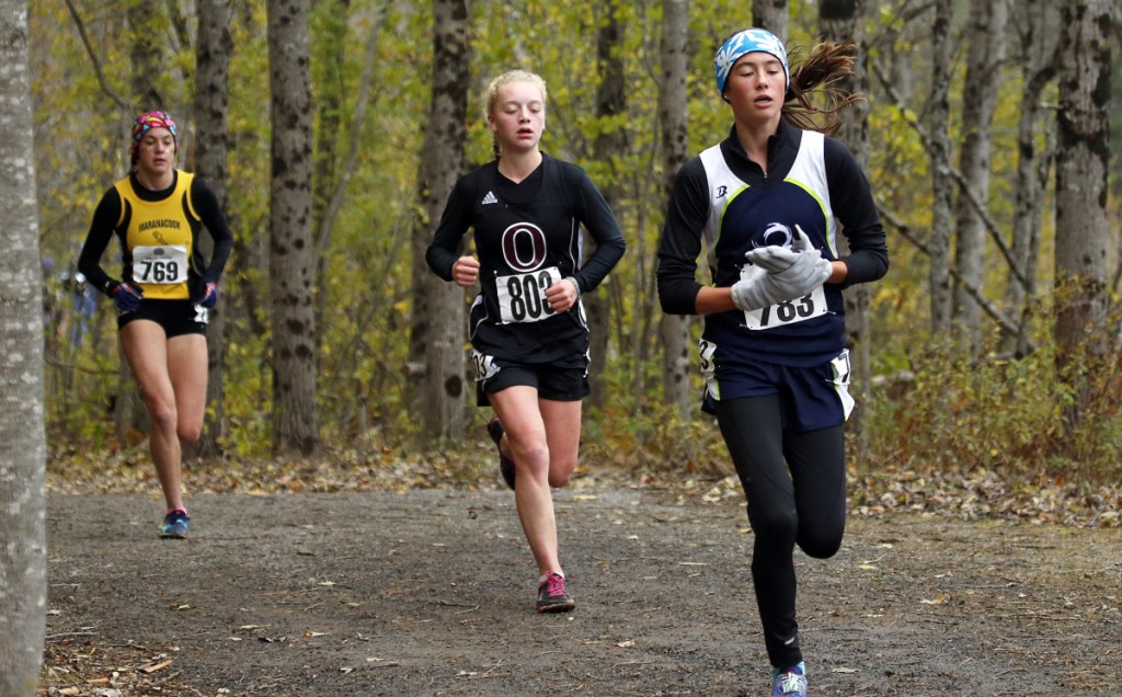 Maine Coast Waldorf's Olivia Reynolds maintains a lead over Orono's Erin Gerbi and Maranacook's Molly McGrail during the Class C girls' race at the cross country state championship in Belfast. Reynolds won in 19:05.87, leading MCW to the team title.