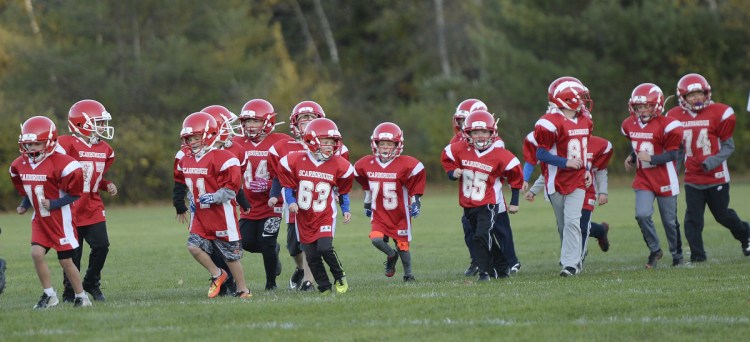 Clinic participants warm up as they run a lap around the field during Scarborough's first "Try Tackle" football clinic in October.