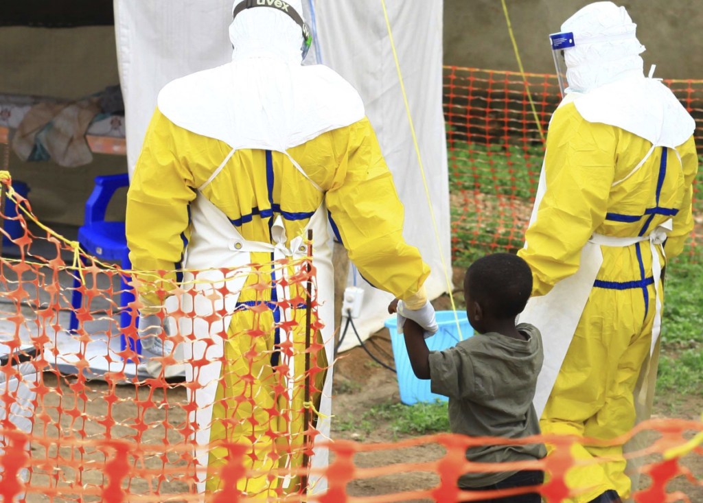 Health workers walk with a boy suspected of having the Ebola virus at an Ebola treatment center in Beni, Eastern Congo, in September.