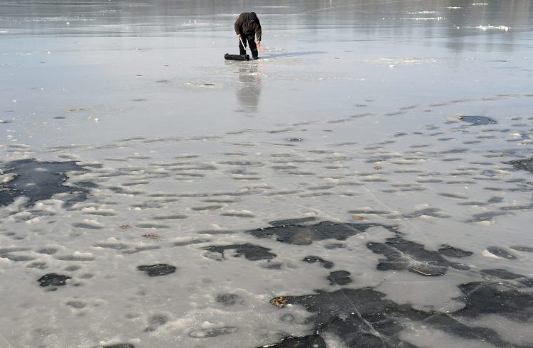 Rob Angelides of Lewiston collects a trap while ice fishing Sunday on Cochnewagon Pond in Monmouth. Cool temperatures have drawn anglers to the ice, which game wardens caution is still very thin on many bodies of water. Angelides said he caught a few small trout after cuting through 6 inches of ice to put out his trap.