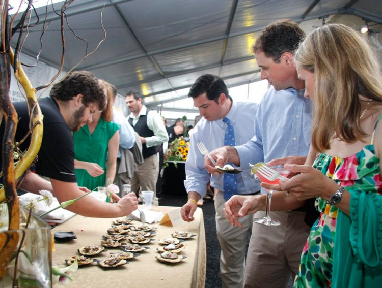 From right, Erin and Kevin Morneault of Falmouth and Mark Simmons of Concord, N.H., watch while Hugo’s chef Andrew Taylor serves Gedalis Farm Goat Taquitos at Taste of the Nation on June 27, 2010. 